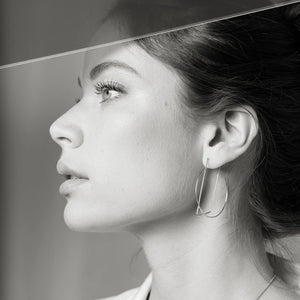 Woman modeling delicate, gold hoop earrings by Truss and Ore