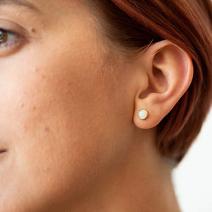 Woman modeling gold opal stud earrings by Truss and Ore